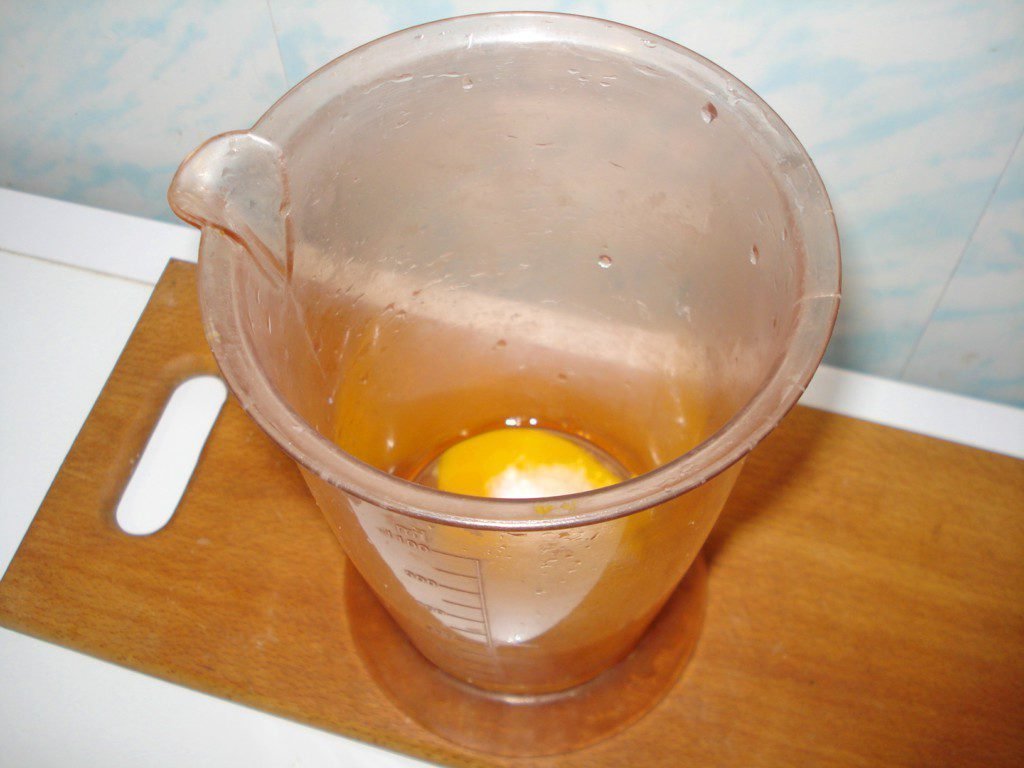 Сырое яйцо в пластиковом мерном стакане