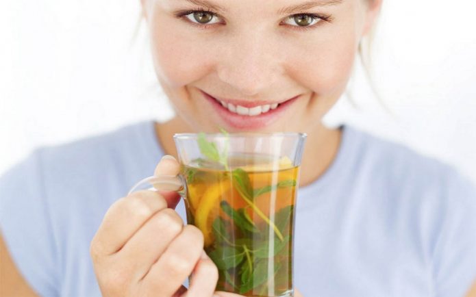 женщина держит к руках стакан зеленого чая с лимоном
