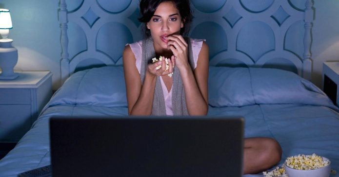 девушка смотрит фильм, кровать, ноутбук, попкорн