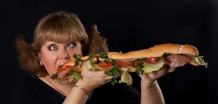 Женщина ест огромный сендвич